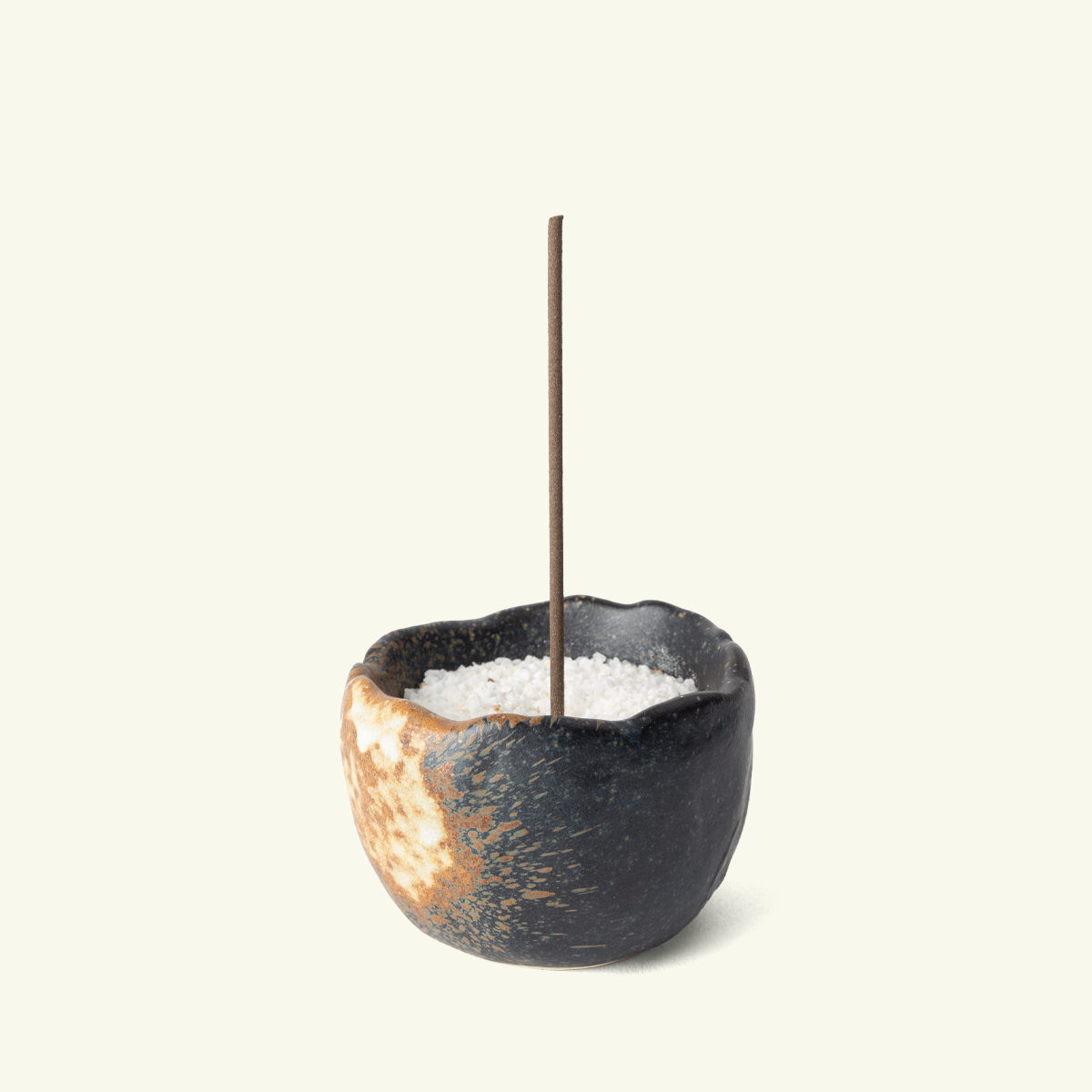 Ishi ceramic Japanese incense holder with a rounded bowl shape, uneven rim and textured dark finish with golden accents.